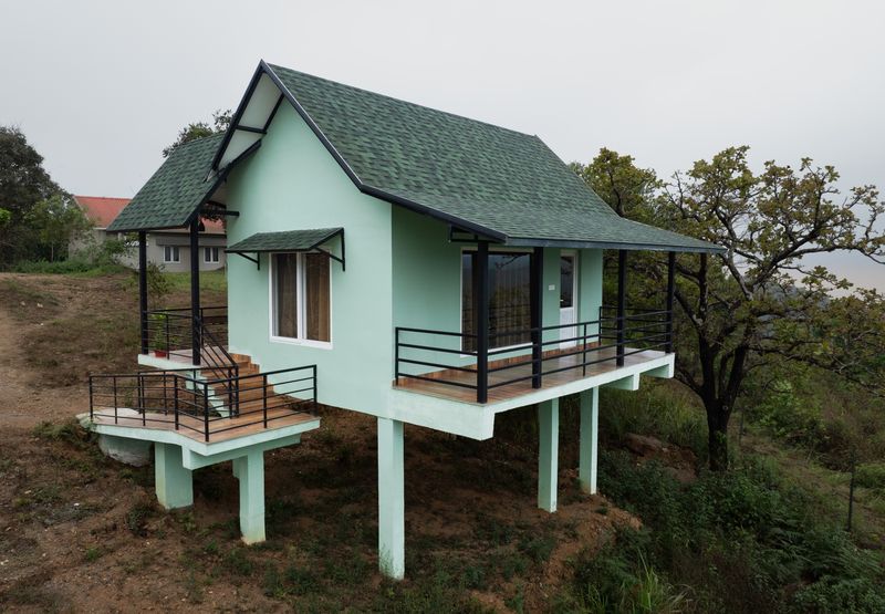 Aerial view of mint cottage on stilts over the hillside